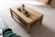 Holz-Couchtisch mit Dekorationen aus der Vogelperspektive, auf einem hellen Teppich stehend.