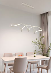 Moderne LED-Hängeleuchte in geschwungenem Design über einem Esstisch, seitliche Perspektive.