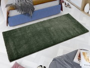 Grüner Uni-Teppich in einem modernen Schlafzimmer, aus der Vogelperspektive fotografiert, neben einem Bett und einem Hocker mit Büchern.