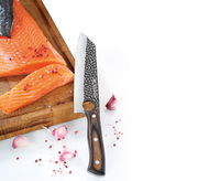 Kochmesser HUNTER 19 cm mit gehämmertem Klingenmuster und Holzgriff, neben Lachsfilet und Knoblauchzehen auf einem Schneidebrett, seitliche Perspektive