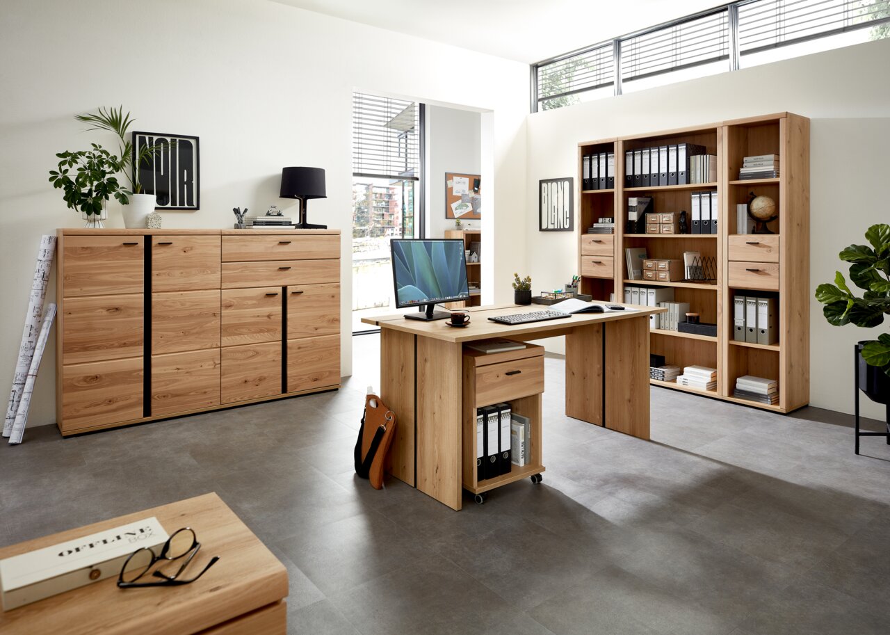 Moderne Büromöbel aus Holz in einem hellen Raum, bestehend aus einem Schreibtisch mit Rollcontainer, einem Aktenschrank und einem großen Regal. Perspektive von vorne.