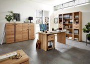 Moderne Büromöbel aus Holz in einem hellen Raum, bestehend aus einem Schreibtisch mit Rollcontainer, einem Aktenschrank und einem großen Regal. Perspektive von vorne.