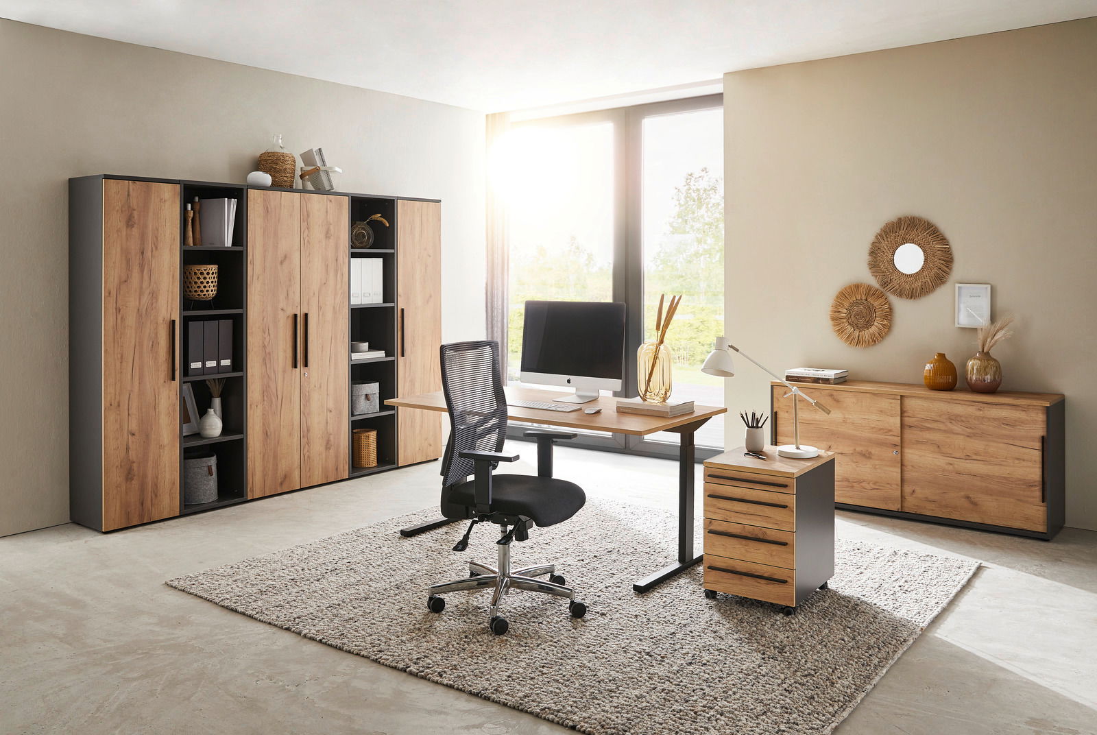 Modernes Büro mit Holzmöbeln, bestehend aus einem Schreibtisch, einem Rollcontainer und mehreren Aktenschränken, seitliche Perspektive.