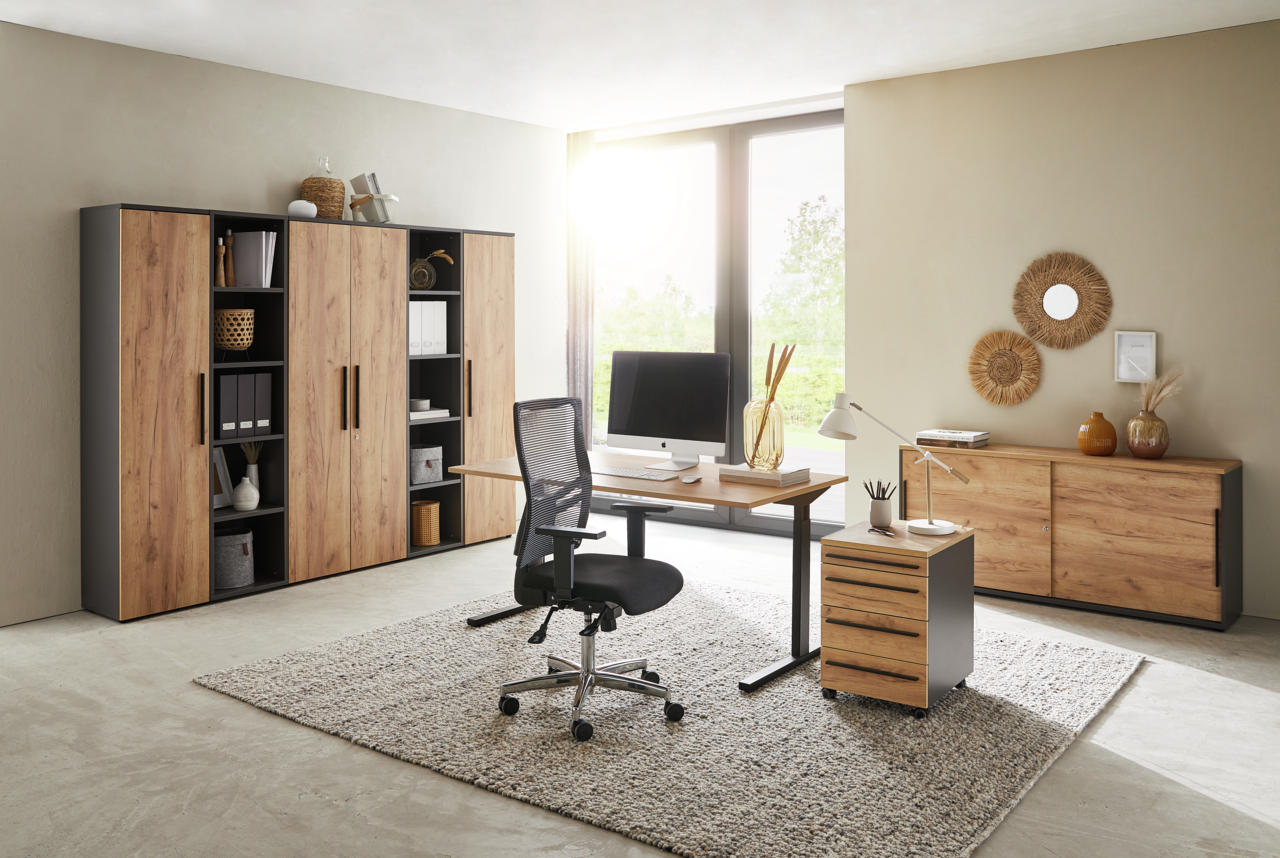 Modernes Büro mit Holzmöbeln, bestehend aus einem Schreibtisch, einem Rollcontainer und mehreren Aktenschränken, seitliche Perspektive.