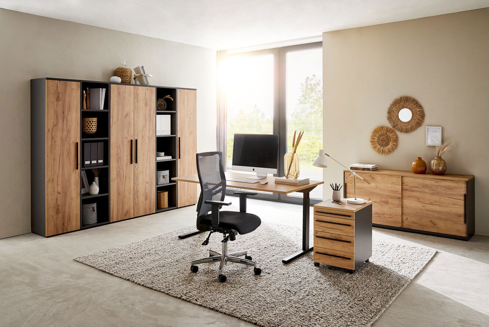 Modernes Büro mit Holzmöbeln, bestehend aus einem Schreibtisch, einem Rollcontainer und mehreren Aktenschränken, seitliche Perspektive.