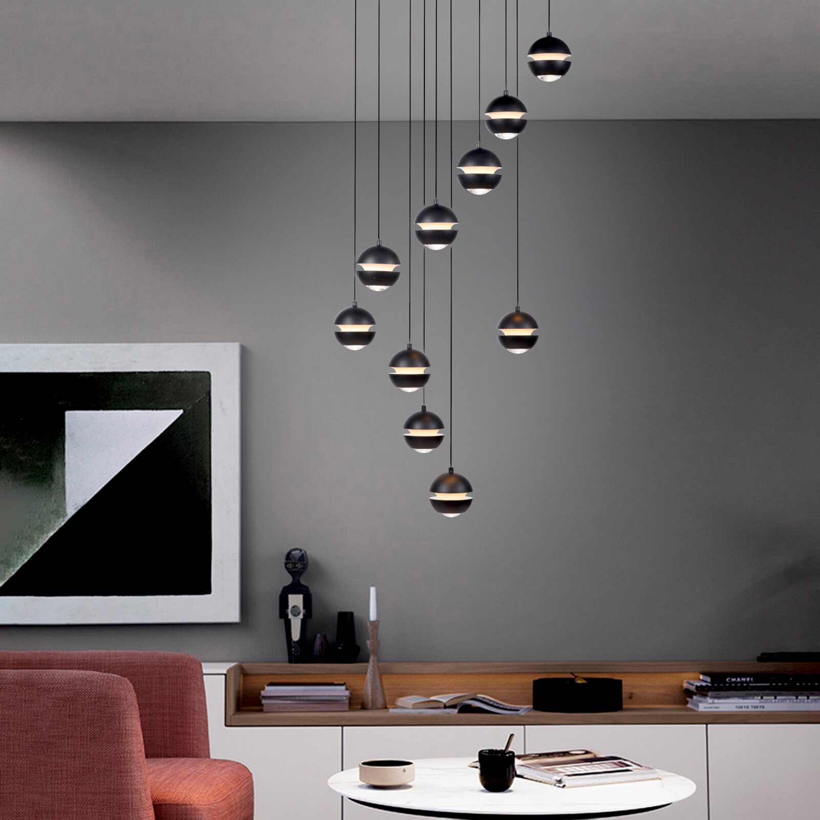 Moderne zwarte bolvormige hanglampen als meervoudige hanglamp met warmwit licht boven een woonkamerbank, zijaanzicht van het interieur vanuit een licht naar beneden gericht perspectief