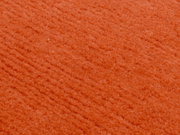 Nahaufnahme eines orangefarbenen Wollteppichs mit weicher Textur.