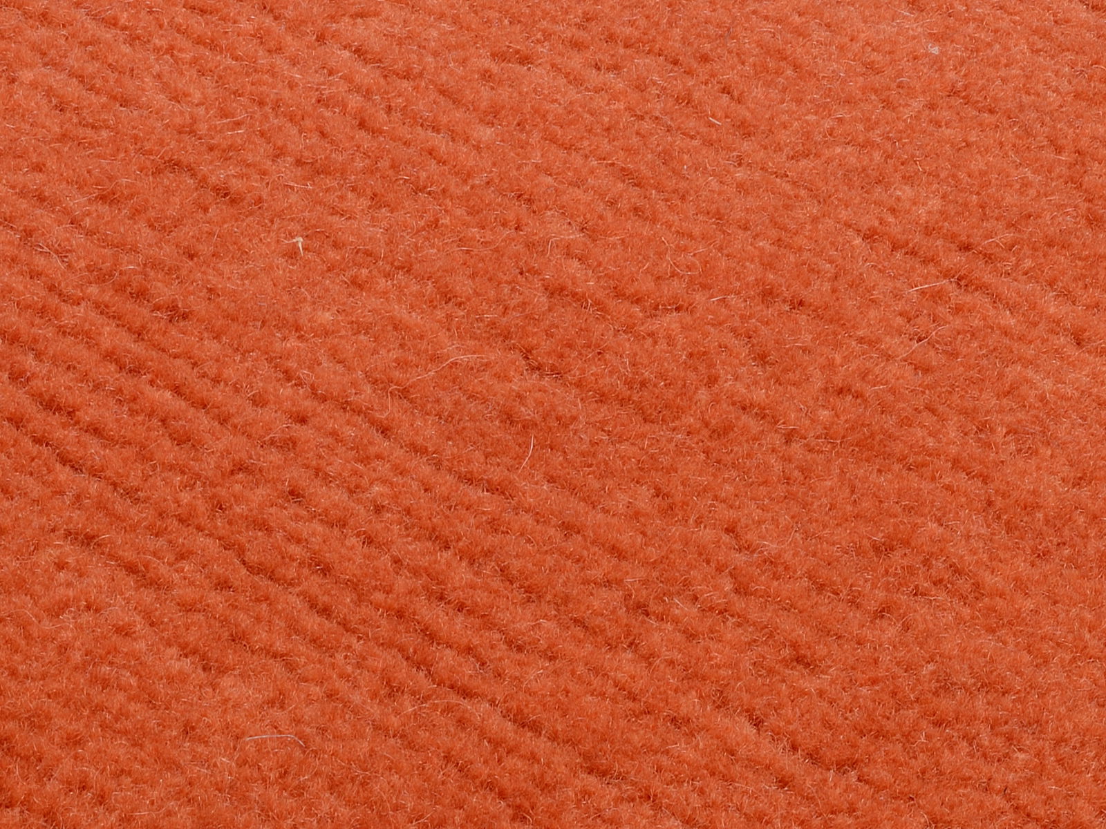 Nahaufnahme eines orangefarbenen Wollteppichs mit weicher Textur.