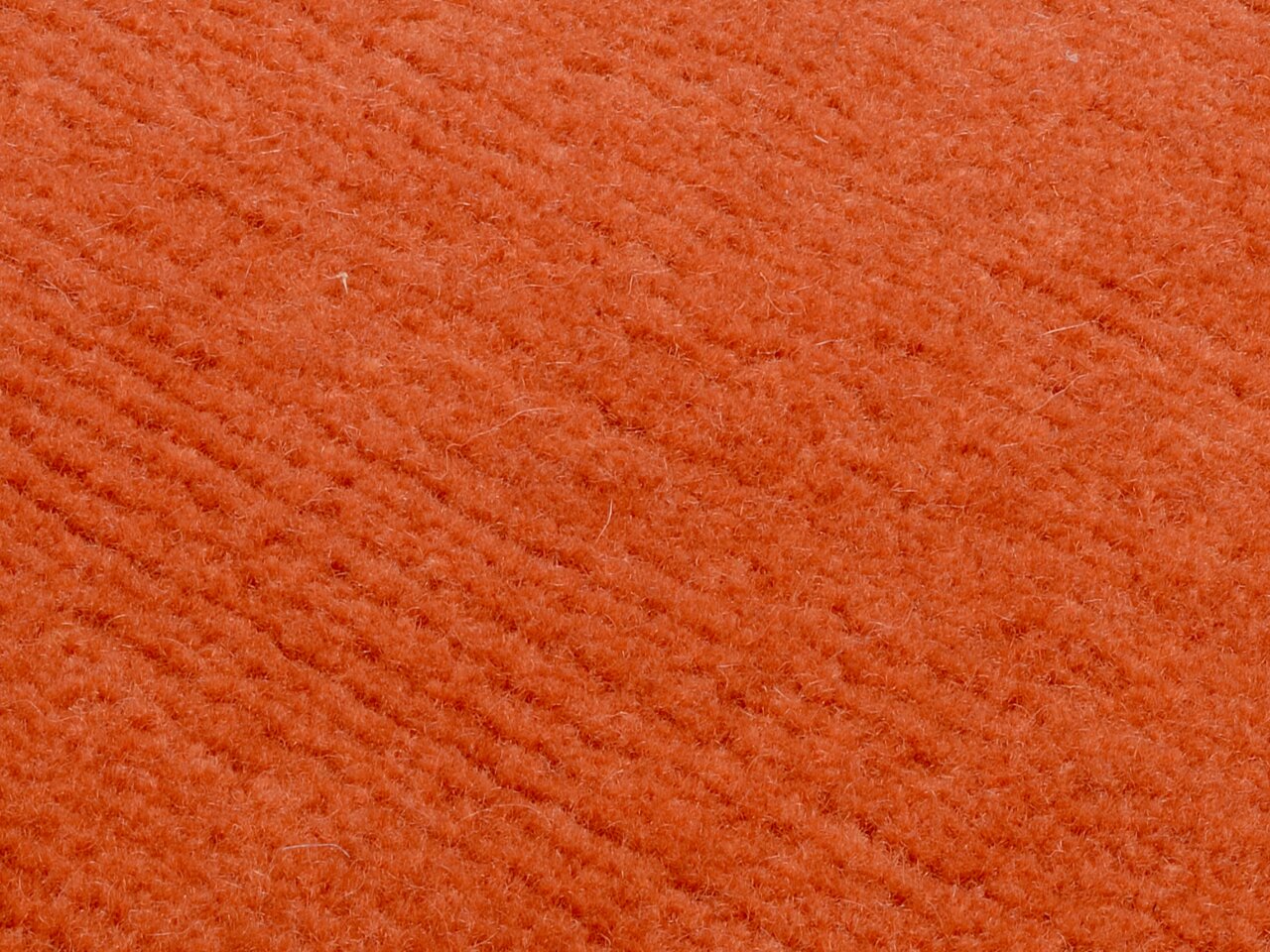 Nahaufnahme eines orangefarbenen Wollteppichs mit weicher Textur.