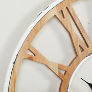 Nahaufnahme einer Wanduhr mit einem Holzrahmen und römischen Ziffern, seitliche Perspektive.