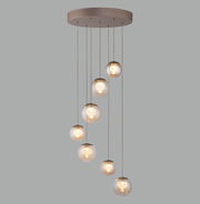 Moderne LED-Pendelleuchte mit sieben kugelförmigen Lampen, die in einer eleganten, absteigenden Anordnung von einer runden Deckenhalterung hängen. Seitenansicht.