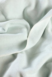 Nahaufnahme einer weichen, hellblauen Wohndecke mit feiner Struktur.