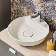 Moderner runder Waschtisch mit glänzendem Wasserhahn, seitliche Perspektive