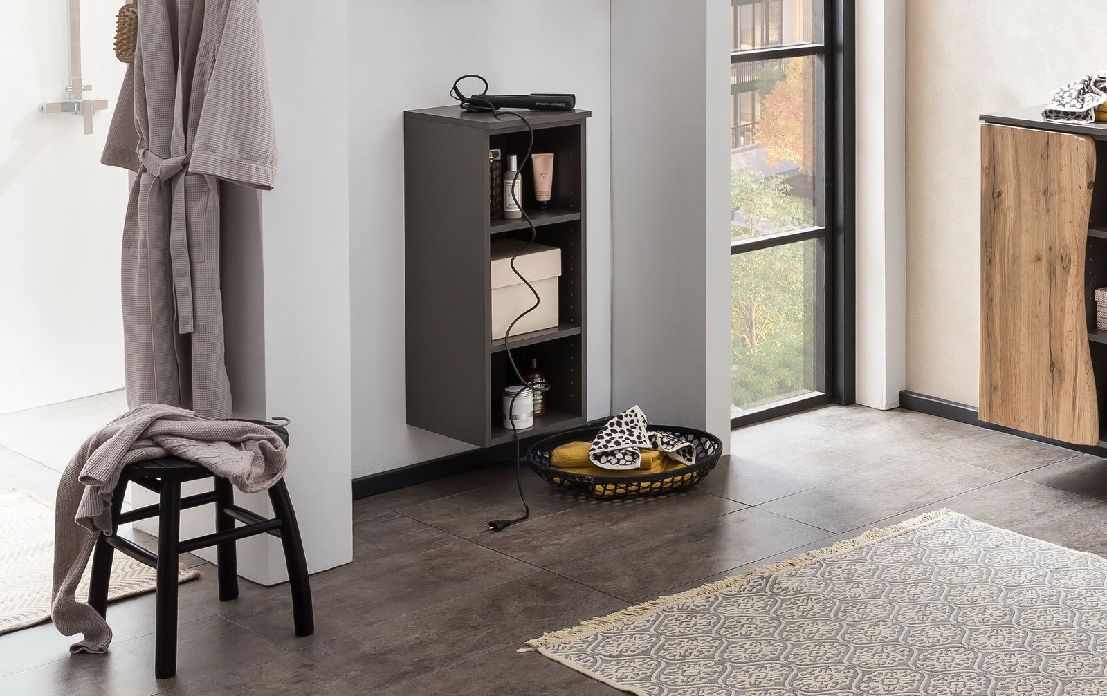 Schwarzes Unterschrank-Regal mit drei Fächern, gefüllt mit Pflegeprodukten und einem Karton, aus seitlicher Perspektive fotografiert.