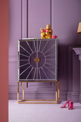 Goldene Gorilla-Dekofigur auf einem modernen, verspiegelten Schrank mit lila Hintergrund, frontal betrachtet.