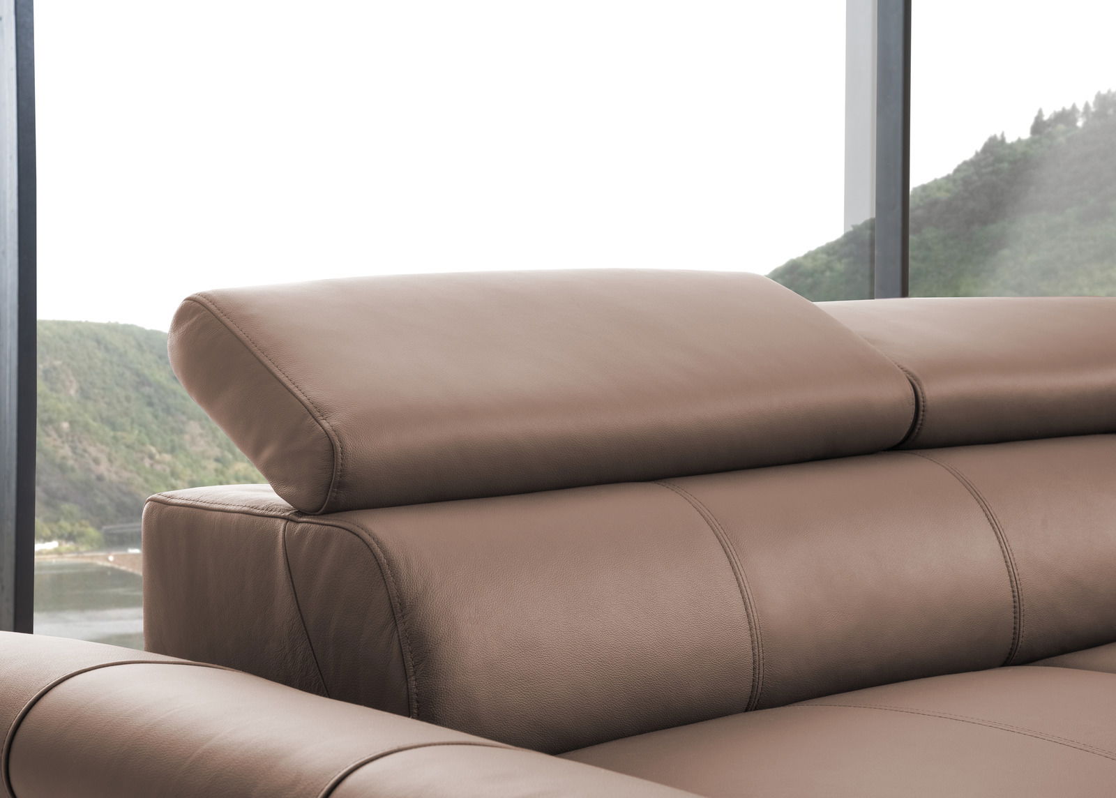 Nahaufnahme einer braunen Ledercouch mit verstellbarer Kopfstütze, seitliche Perspektive.