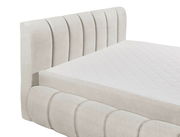 Seitliche Ansicht eines eleganten Polsterbetts mit gestepptem Kopfteil und weißer Matratze.