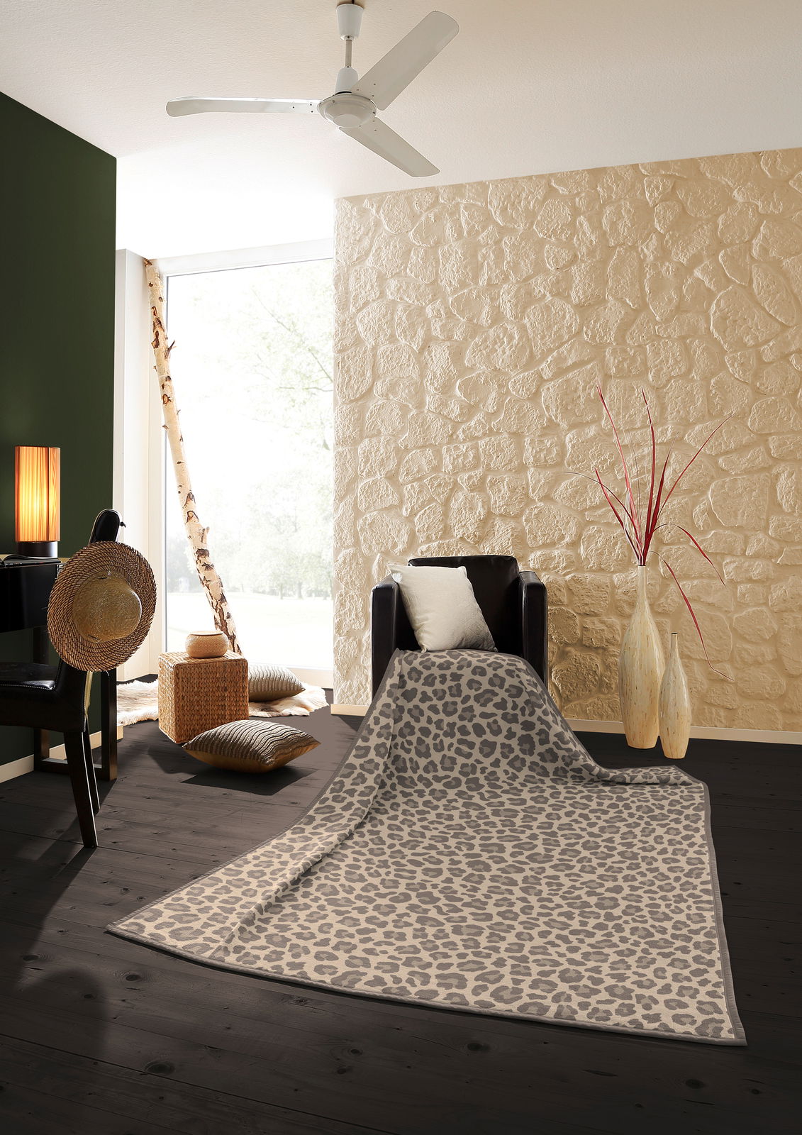 Leopardengemusterte Wohndecke in einem stilvollen Wohnzimmer, drapiert über einem Sessel, mit Blick auf eine moderne Einrichtung mit Steinwand und Holzboden.