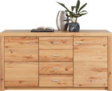 Frontale Ansicht eines Sideboards aus hellem Holz mit mehreren Schubladen und Türen, dekoriert mit einer Vase und einer Pflanze.