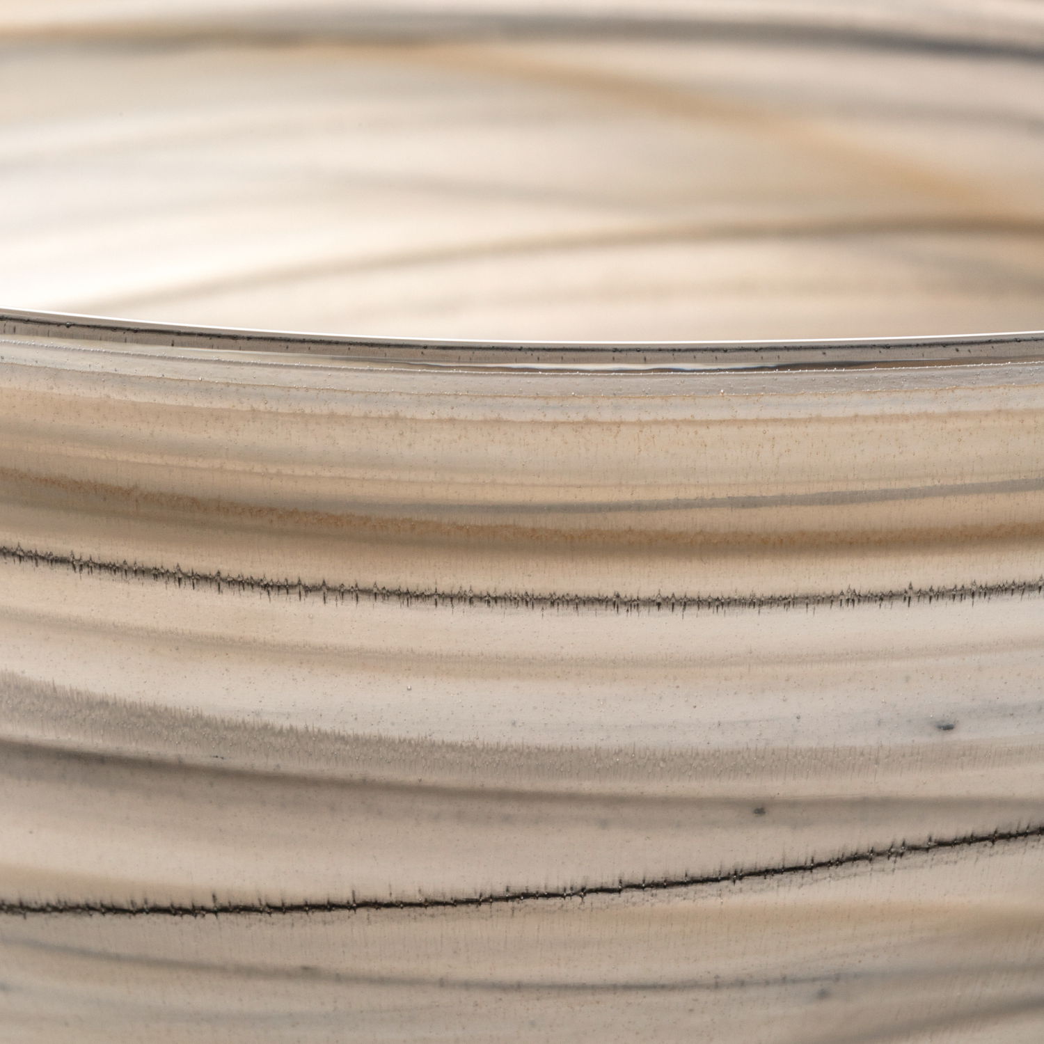 Nahaufnahme einer Schale ALABASTRO in Beige und Schwarz mit feinen, horizontalen Linien und einer glatten Oberfläche.