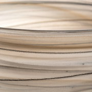 Close-up van een ALABASTRO-schaal in beige en zwart met fijne, horizontale lijnen en een glad oppervlak.