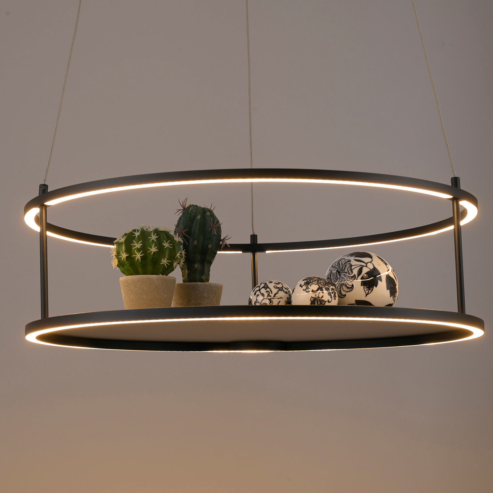 Moderne LED-Pendelleuchte mit zwei Ringen, dekoriert mit kleinen Kakteen und kunstvollen Kugeln, seitliche Perspektive.