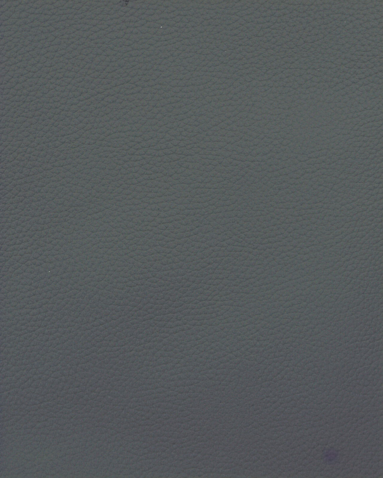 Nahaufnahme einer dunkelgrauen, strukturierten Lederoberfläche, von oben betrachtet.