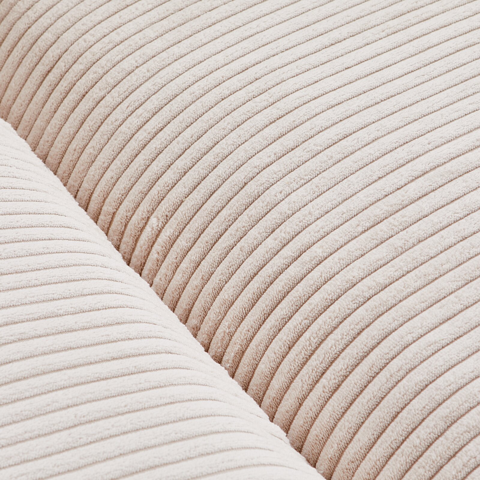 Close-up van een grote bank met een crèmekleurige, geribbelde stoffen bekleding, detailopname van de textuur.
