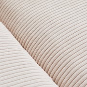 Close-up van een grote bank met een crèmekleurige, geribbelde stoffen bekleding, detailopname van de textuur.