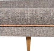 Detailansicht von vorne: graubraun melierter Stoffbezug eines Sofas/Polstermöbels mit umlaufender Naht und konischem Holzfuß