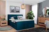 Boxspringbett 140 in einem modernen Schlafzimmer, seitliche Perspektive, mit grüner Bettwäsche und Holzmöbeln.
