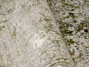 Nahaufnahme eines Designer-Teppichs mit abstraktem Muster in Grün- und Beigetönen, perspektivisch von der Seite aufgenommen.