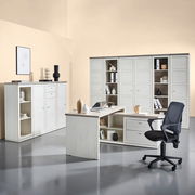 Moderner Eckschreibtisch in heller Holzoptik mit integriertem Stauraum, umgeben von passenden Schränken und einem Bürostuhl, aus der Perspektive eines Betrachters im Raum.