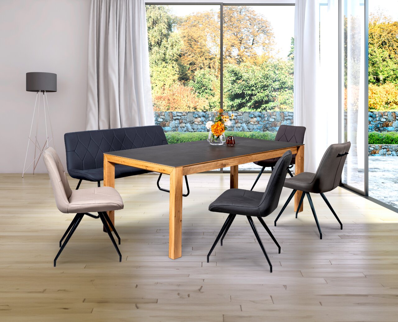 Linea Natura Esstisch BELLAGIO Moderner Esstisch aus Holz mit dunkler Tischplatte, umgeben von stilvollen Stühlen in einem hellen Raum mit großen Fenstern. Perspektive von schräg vorne.