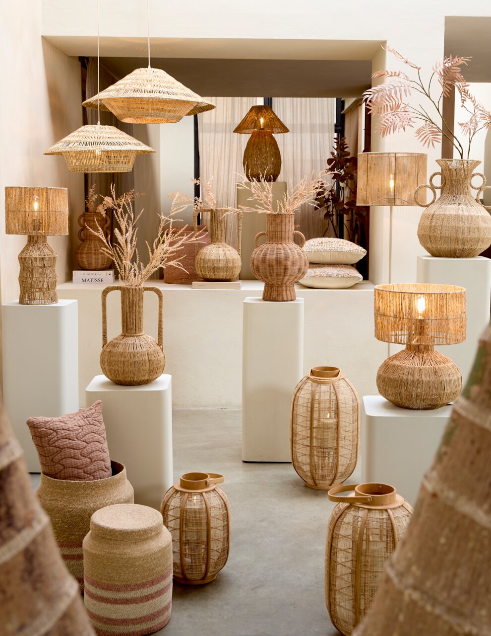 Vase aus geflochtenem Material, umgeben von anderen dekorativen Objekten, aus der Frontalperspektive fotografiert.