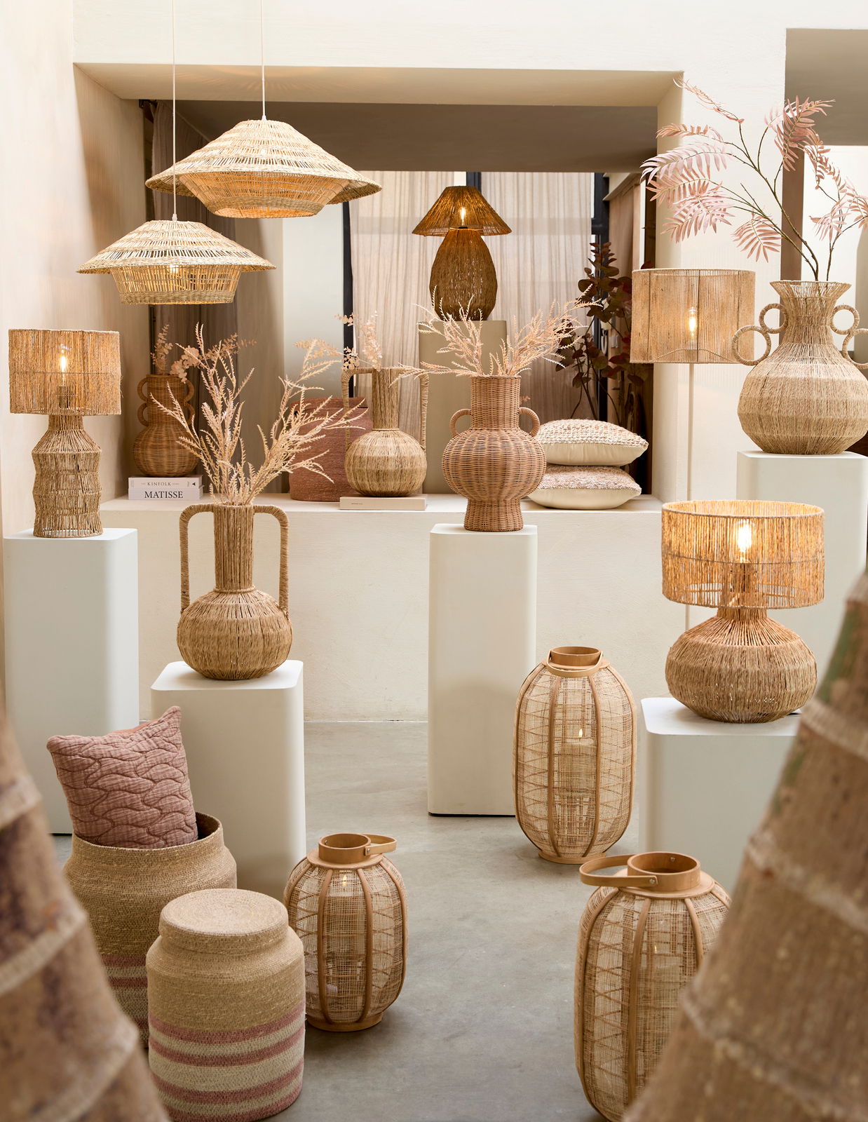 Vase aus geflochtenem Material, umgeben von anderen dekorativen Objekten, aus der Frontalperspektive fotografiert.