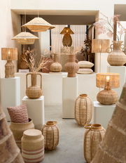 Vase aus geflochtenem Material, umgeben von anderen dekorativen Objekten, aus der Frontalperspektive fotografiert.