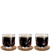 Drei Kaffeegläser mit wellenförmigem Design, gefüllt mit schwarzem Kaffee, auf runden Untersetzern, aus frontaler Perspektive.