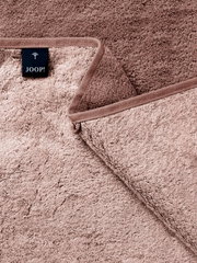 Nahaufnahme eines taupefarbenen JOOP! Frottee-Handtuchs mit umlaufender Bordüre und eingenähtem Markenlabel, schräg von oben fotografiert.