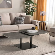 Moderner Couchtisch mit dunkler, rechteckiger Tischplatte und schwarzem Metallgestell, in einem stilvoll eingerichteten Wohnzimmer mit Sofa und Pflanzen, seitliche Perspektive.