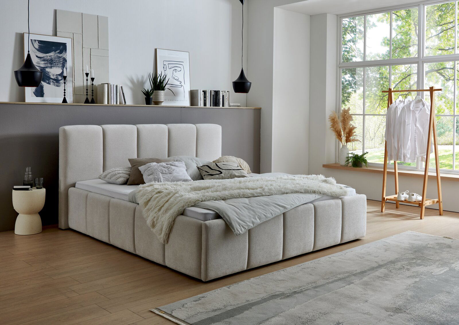 Modernes Polsterbett in einem stilvollen Schlafzimmer mit großen Fenstern, seitliche Perspektive