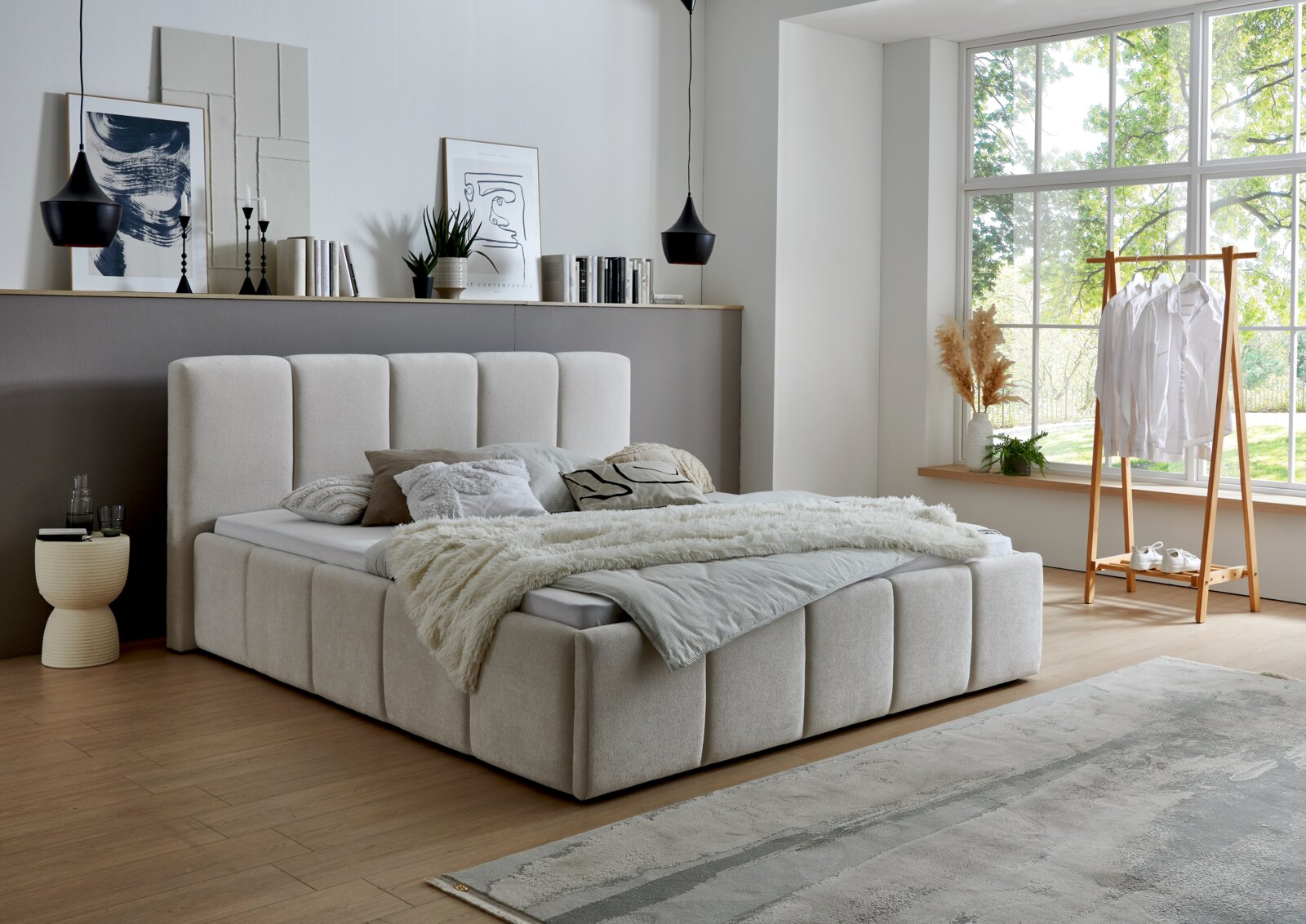 Modernes Polsterbett in einem stilvollen Schlafzimmer mit großen Fenstern, seitliche Perspektive