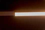 Moderne rechthoekige LED-plafondlamp met warme gloed, gefotografeerd van onderen in perspectief tegen een donkere achtergrond