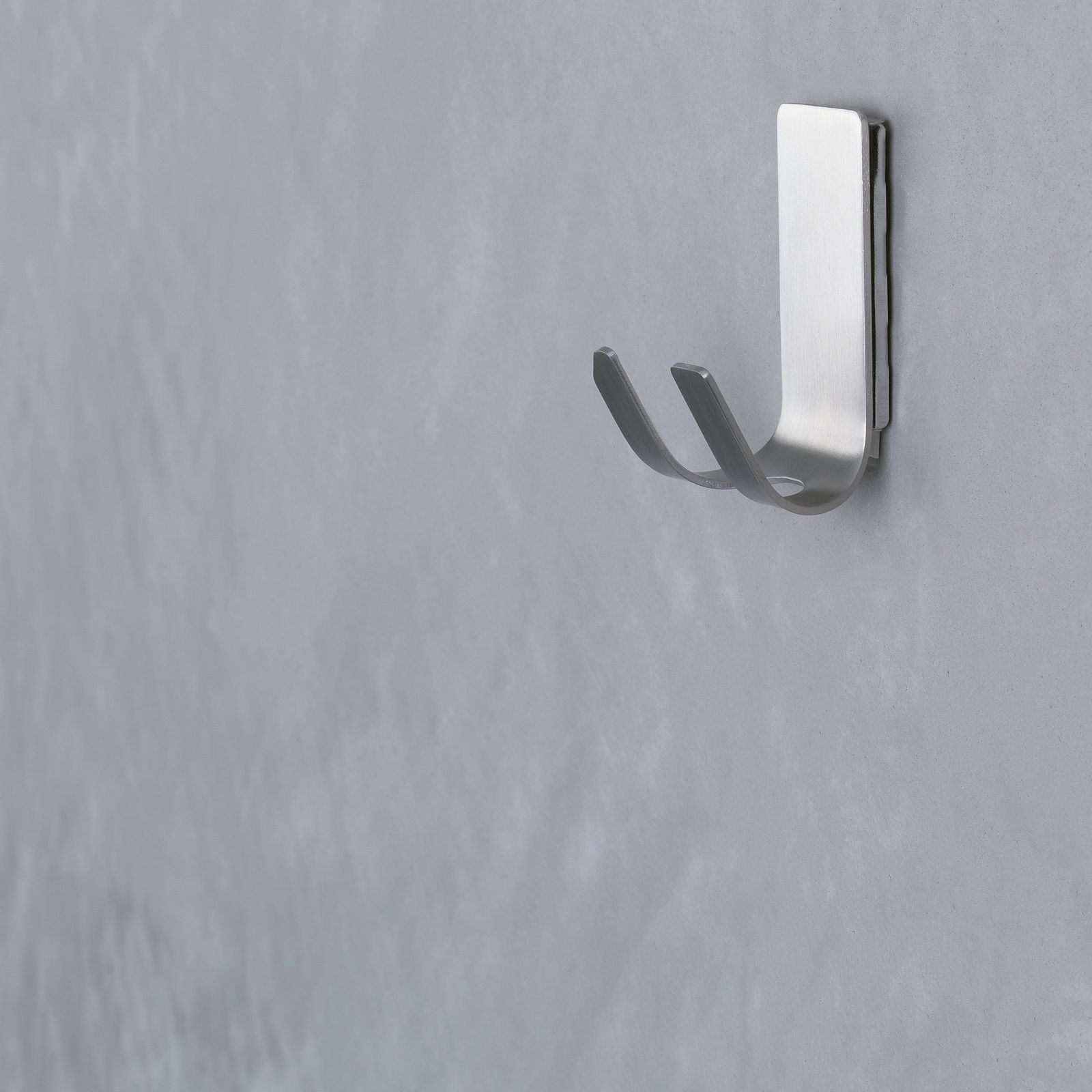 Wandhaken aus Metall, seitliche Perspektive, an einer grauen Wand befestigt