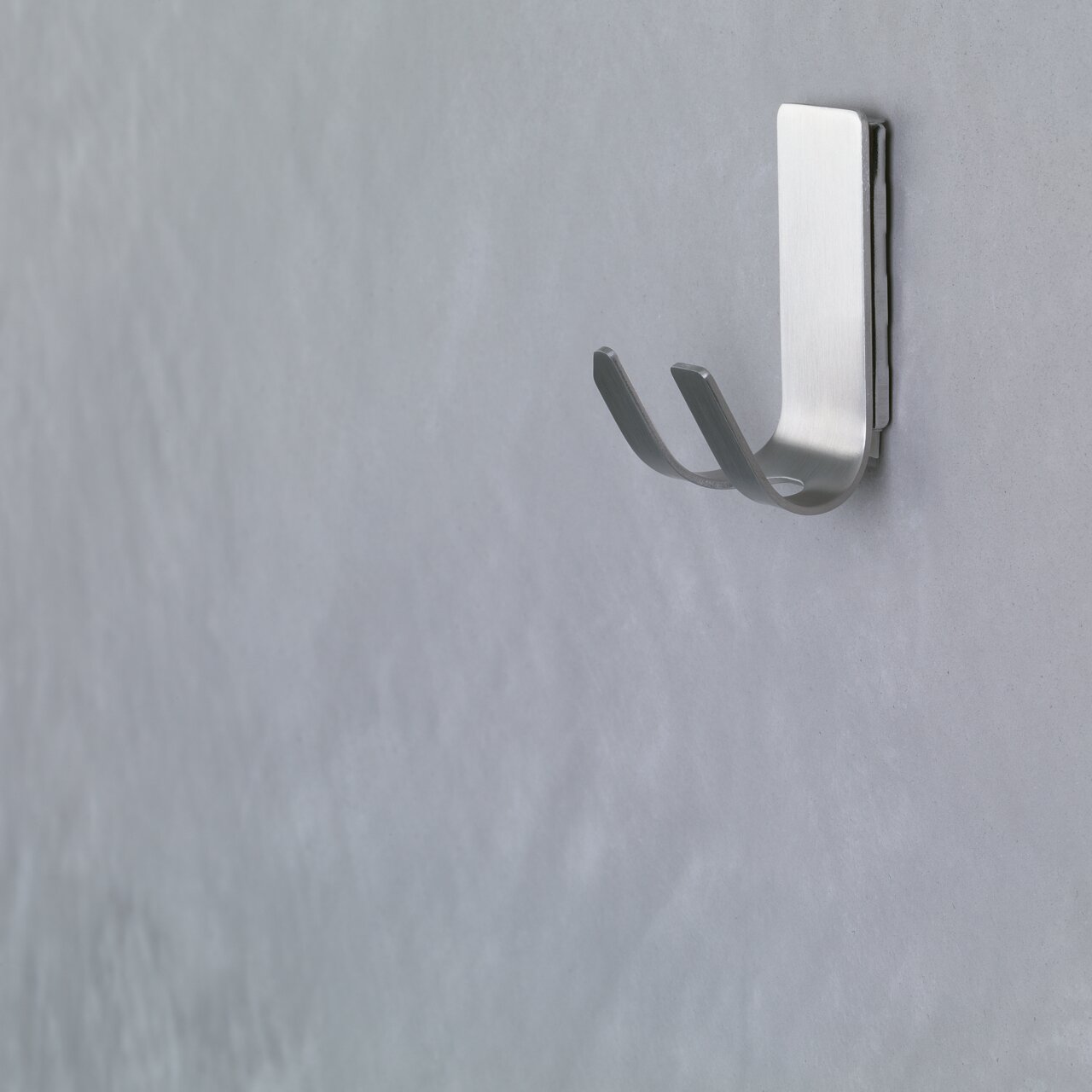 Wandhaken aus Metall, seitliche Perspektive, an einer grauen Wand befestigt