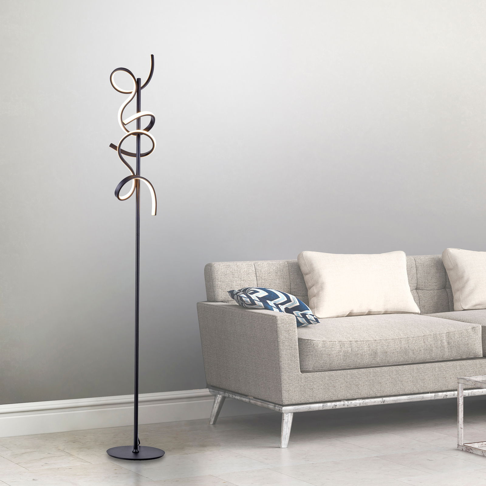 Moderne Stehleuchte CURLS mit geschwungenem Design, seitliche Perspektive neben einem grauen Sofa.