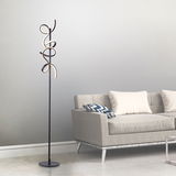 Moderne Stehleuchte CURLS mit geschwungenem Design, seitliche Perspektive neben einem grauen Sofa.