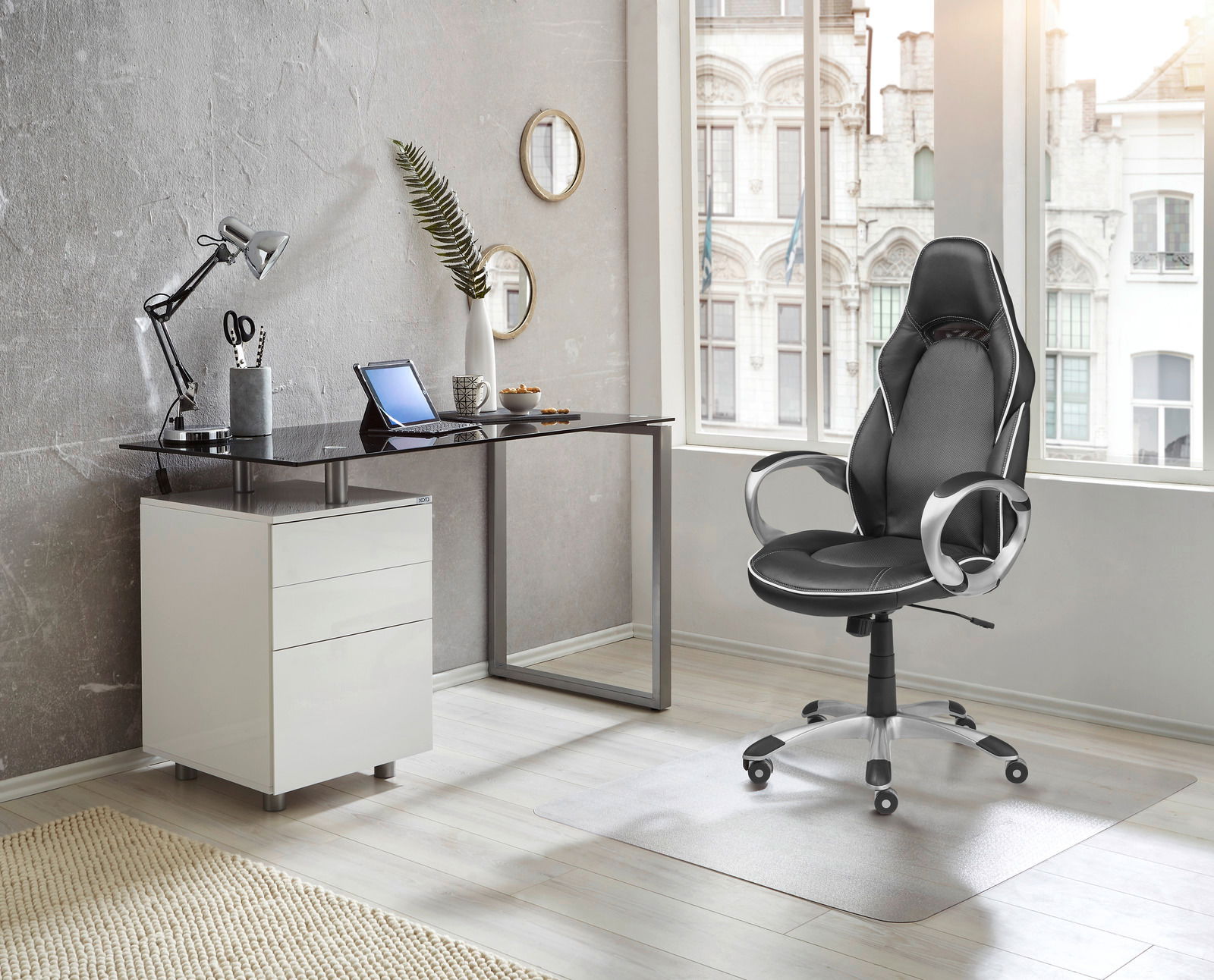 Moderner Schreibtisch mit Glasplatte und weißem Unterschrank, seitliche Perspektive, in einem stilvollen Büro mit ergonomischem Bürostuhl.
