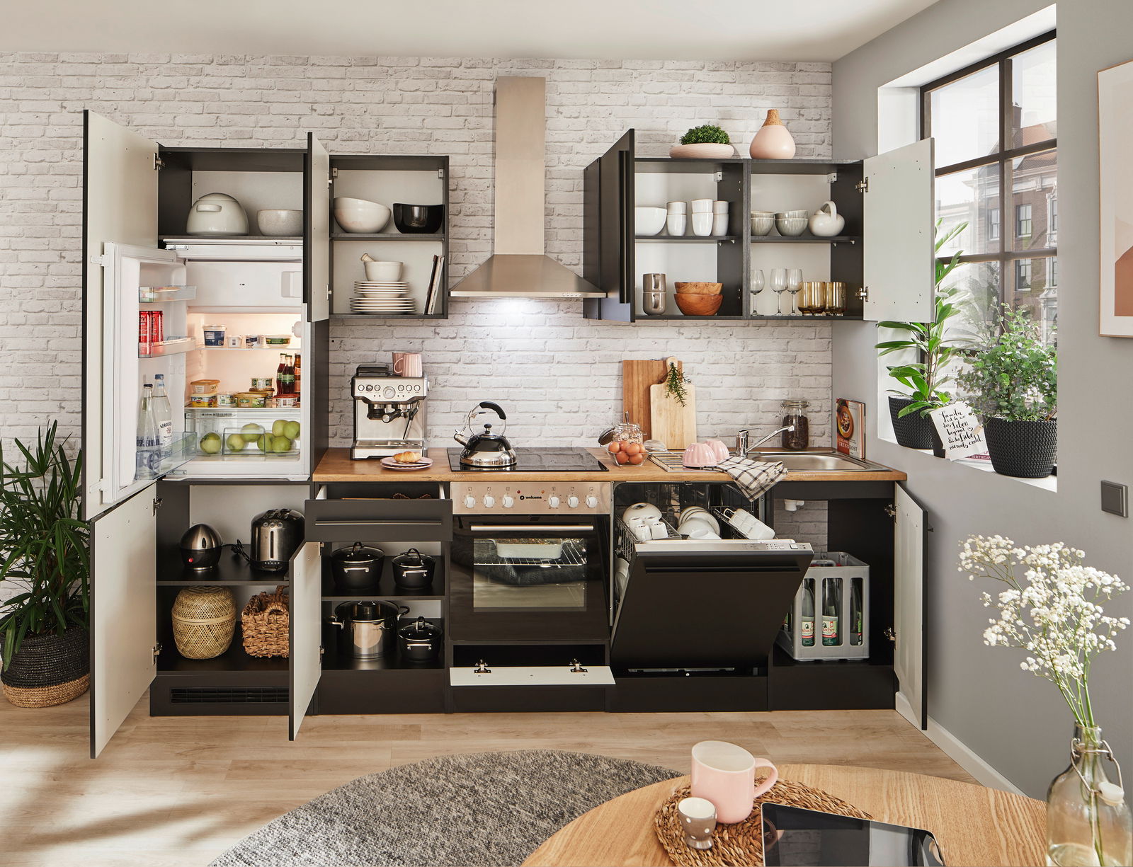 Moderne Küchenzeile mit offenen Schränken, Kühlschrank, Herd und Spüle, aus der Perspektive des Essbereichs fotografiert.