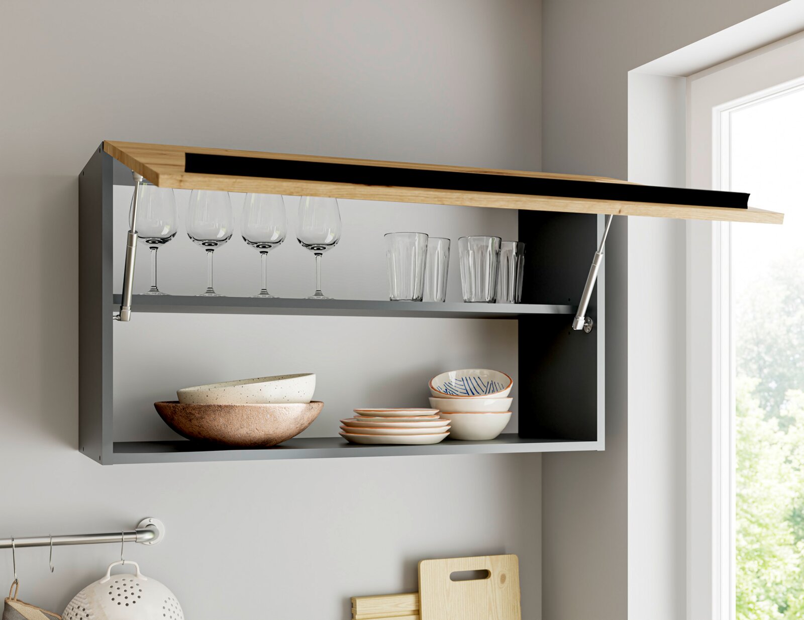 Wandhängender Küchen-Oberschrank in Anthrazit mit nach oben klappbarer Holzfront und Gasdruckdämpfern, geöffnet und mit Gläsern sowie Geschirr bestückt, Ansicht schräg von vorn